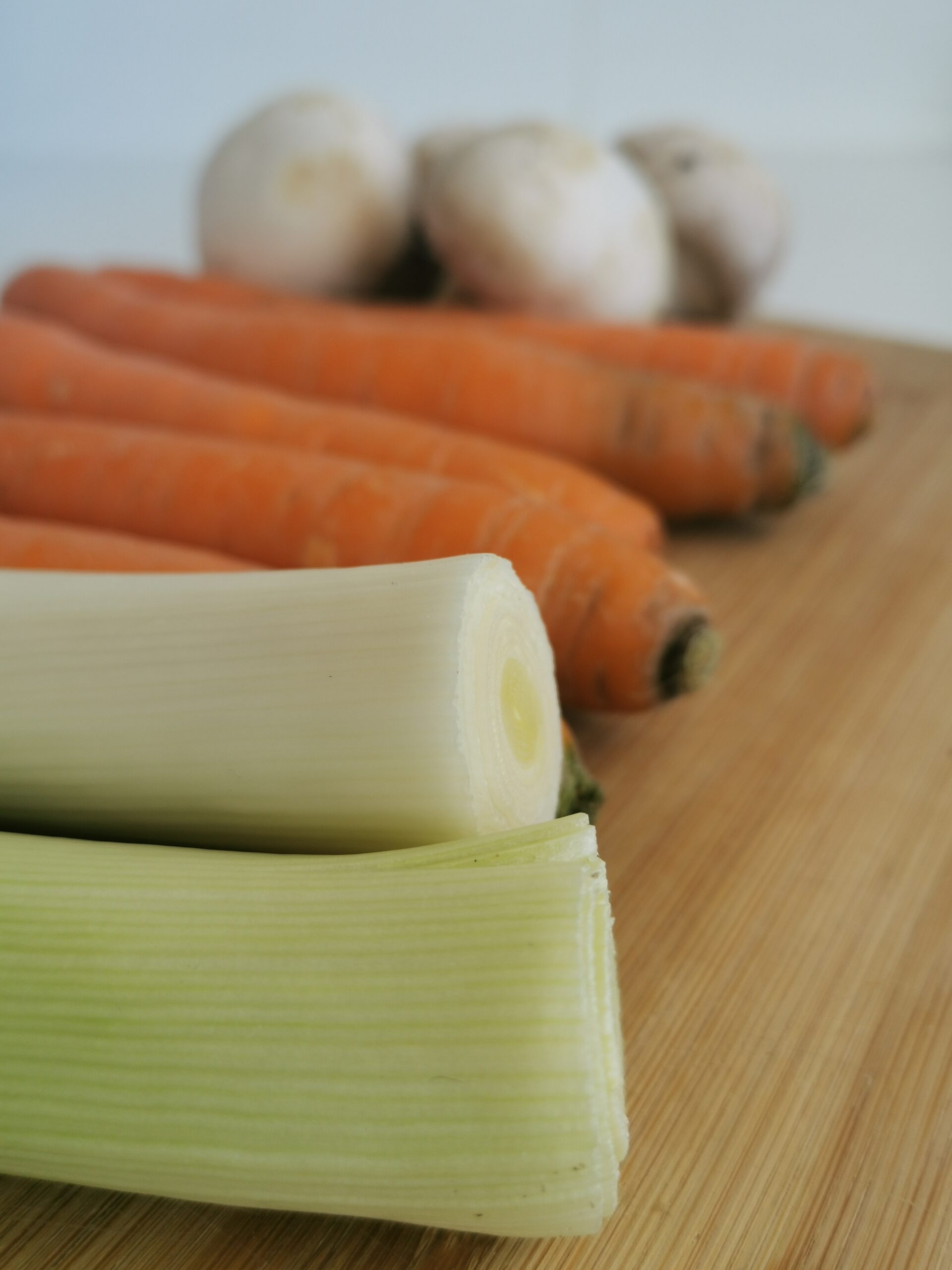 gros plan sur des légumes : poireaux, carottes et champignons en arrière plan