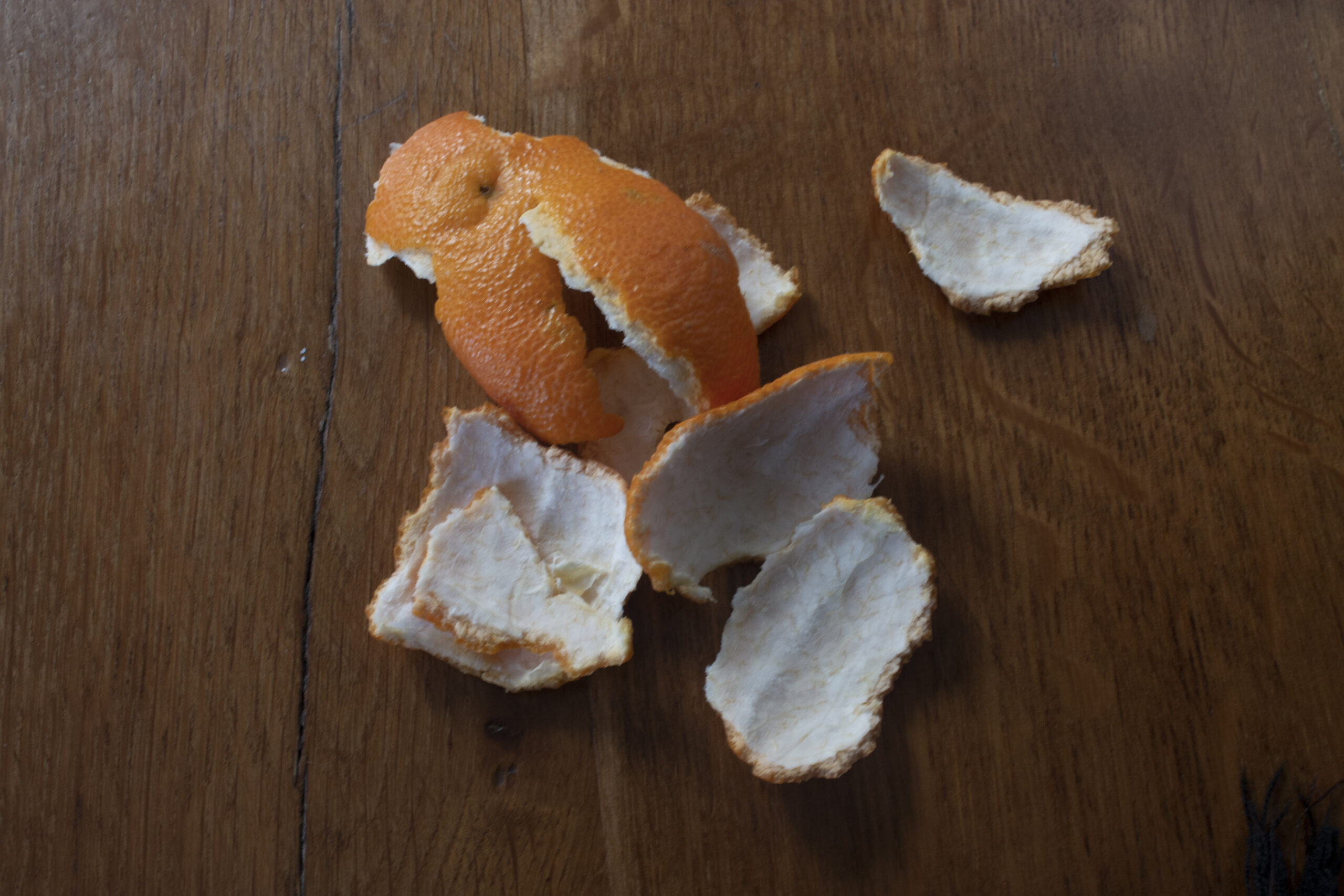 La peau orange d'une clémentine épluchée sur une table en bois.