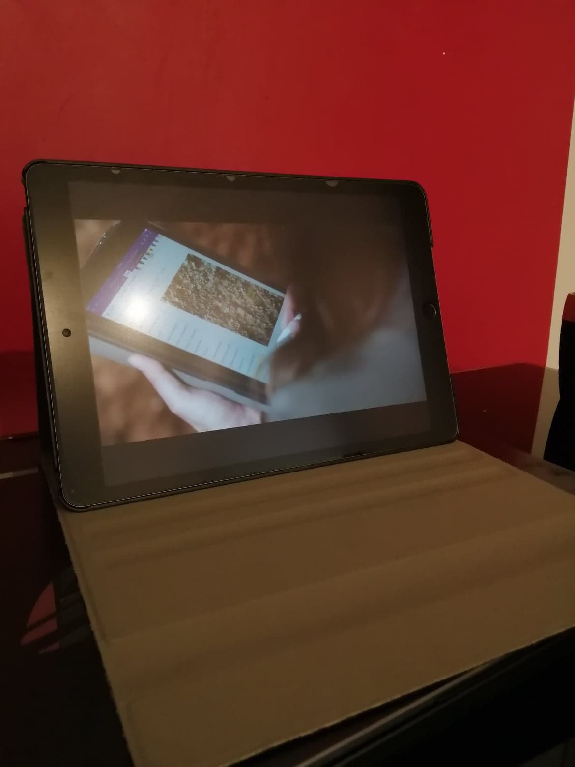 Photo d'une tablette tactile de type iPad, l'écran allumé et posé sur un bureau noir.