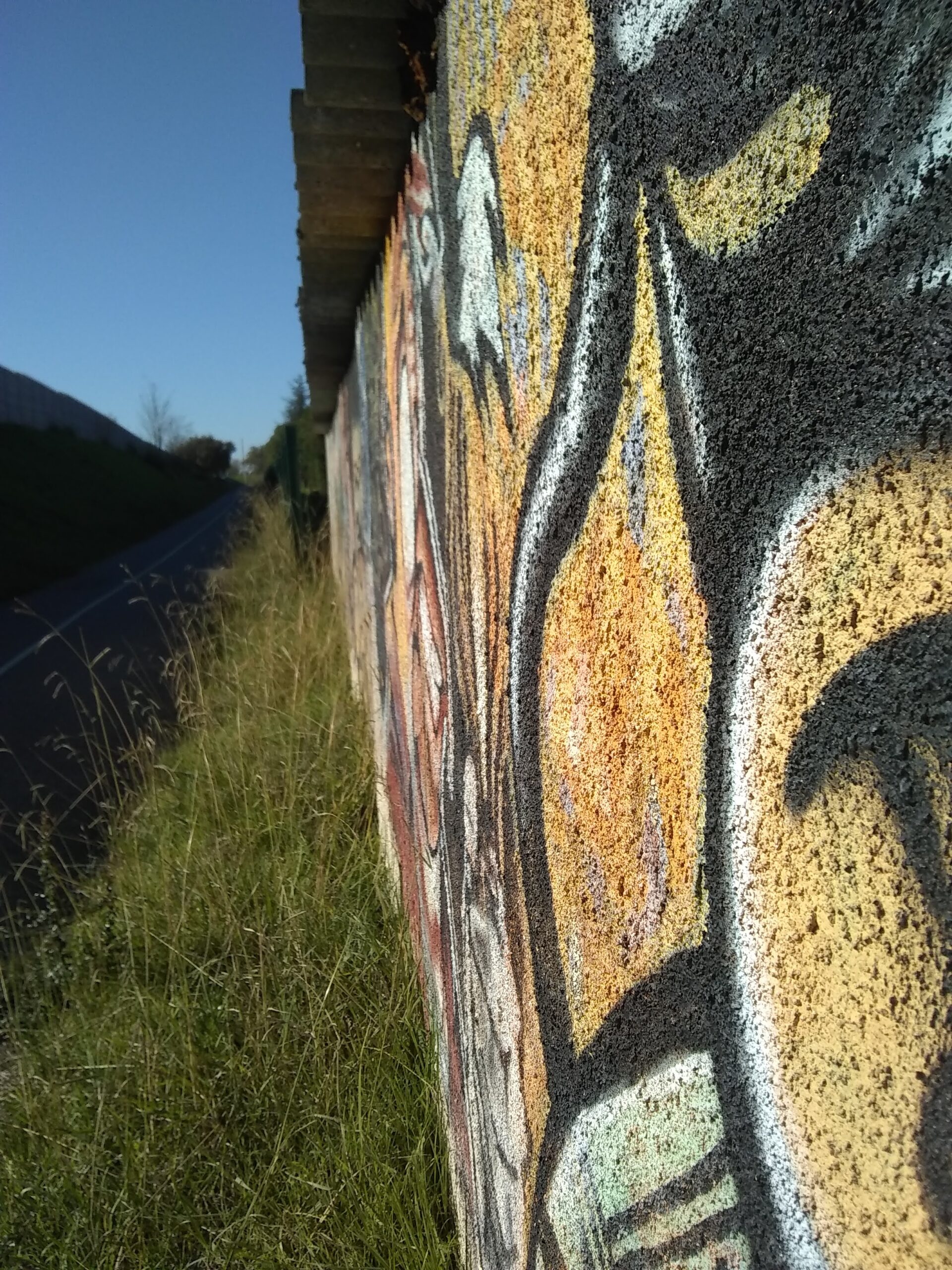 Photo prise le long d'un mur graffé. On perçoit la texture du béton, rigide, dur et sa surface pleine de petits trous.