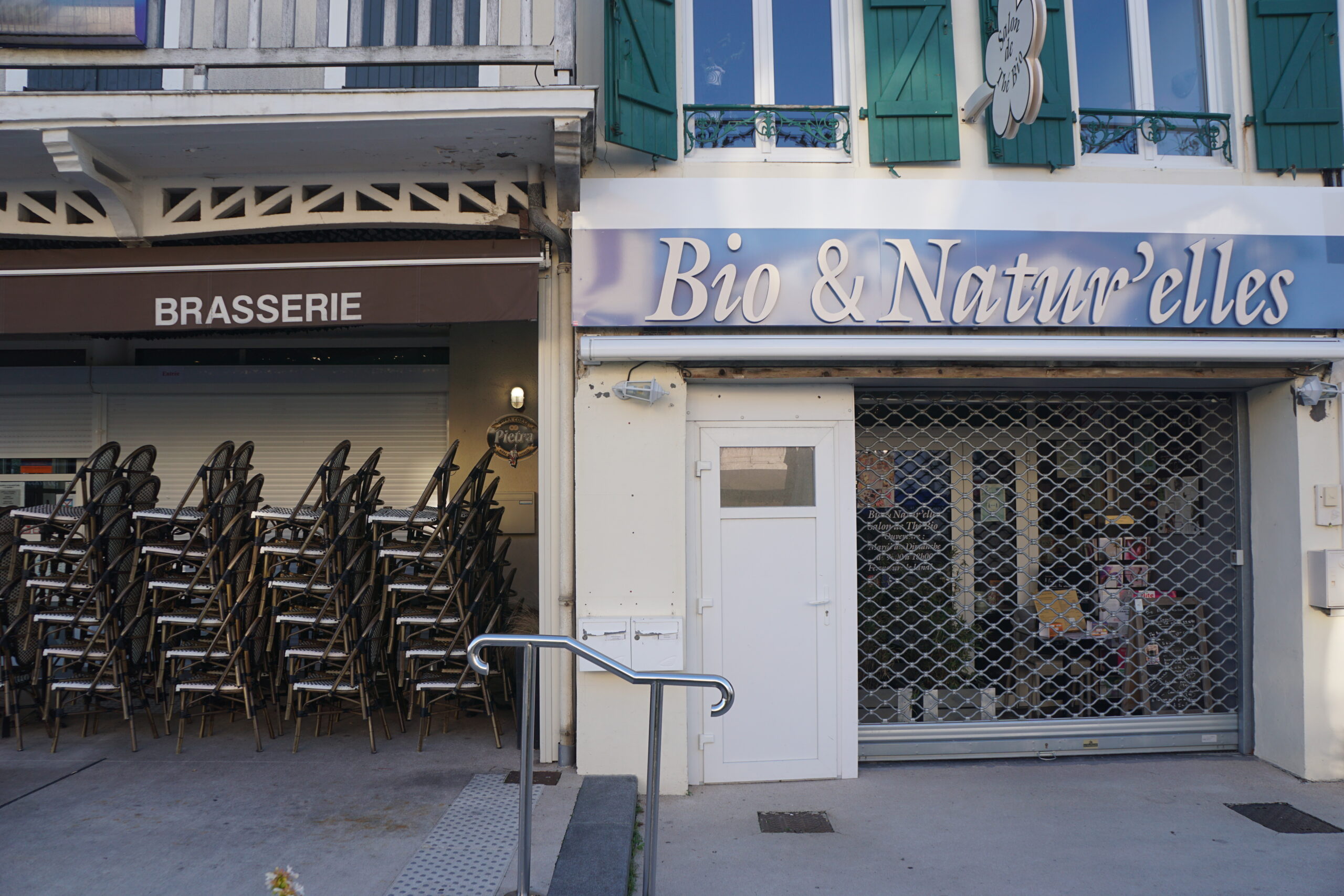 Photographie des devantures d'une boutique et d'un café, fermées.