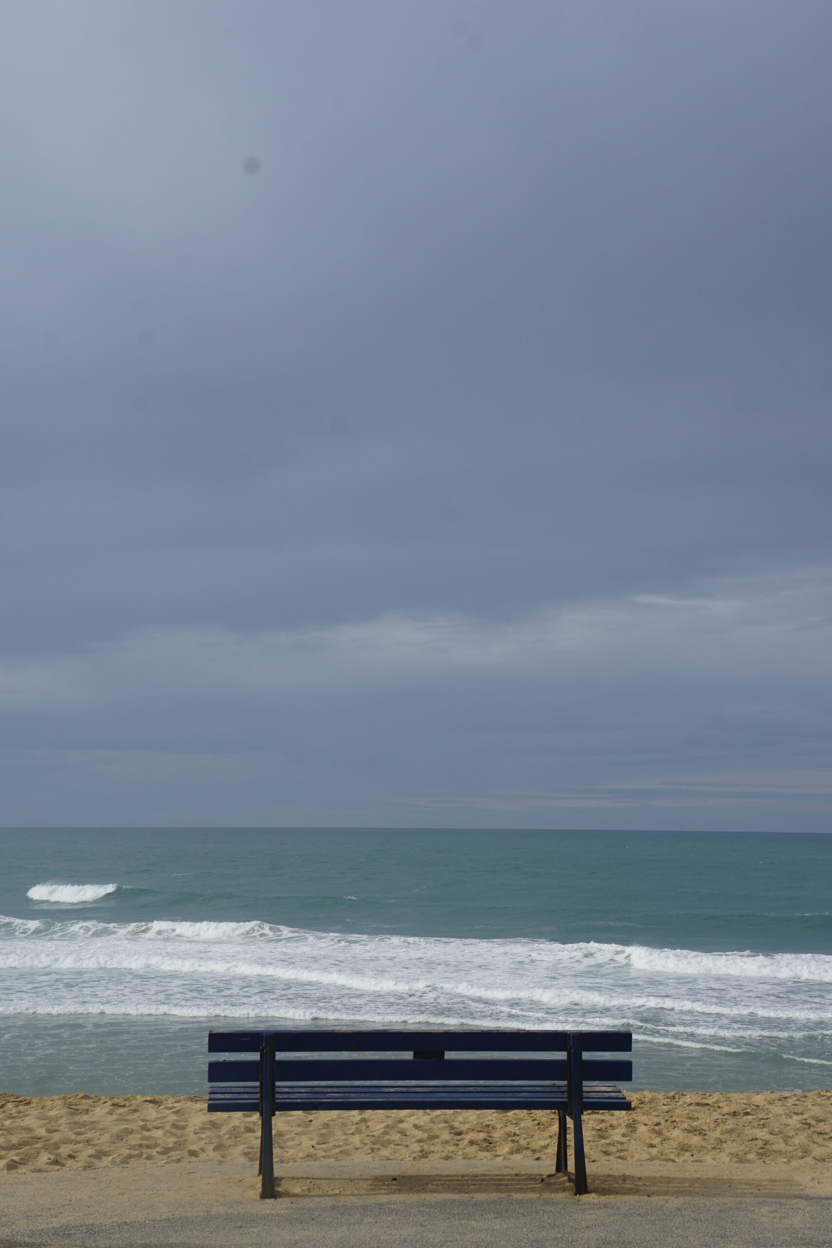 Photographie d'un banc vide face à l'océan.