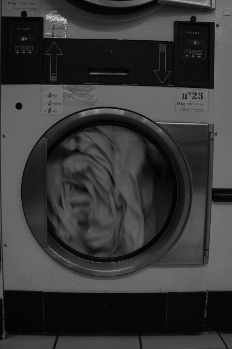 Une sécheuse en route qui brasse du linge. L'image est en noir et blanc.