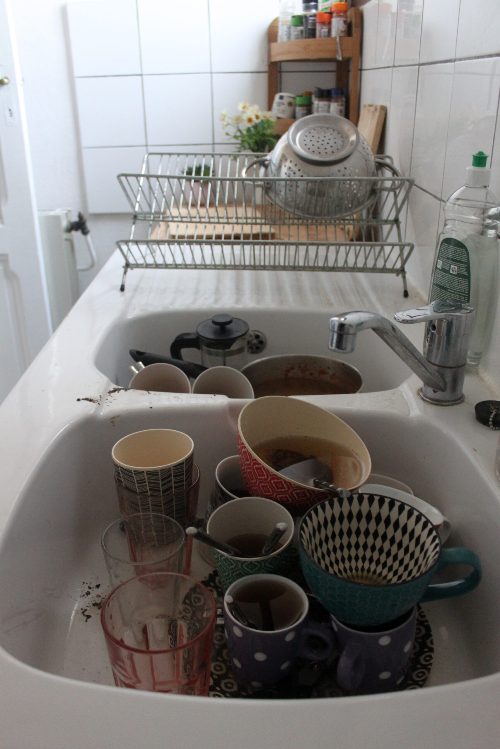 Une pile de vaisselle est dans l'évier de la cuisine. Principalement des tasses car Nina boit beaucoup de café.