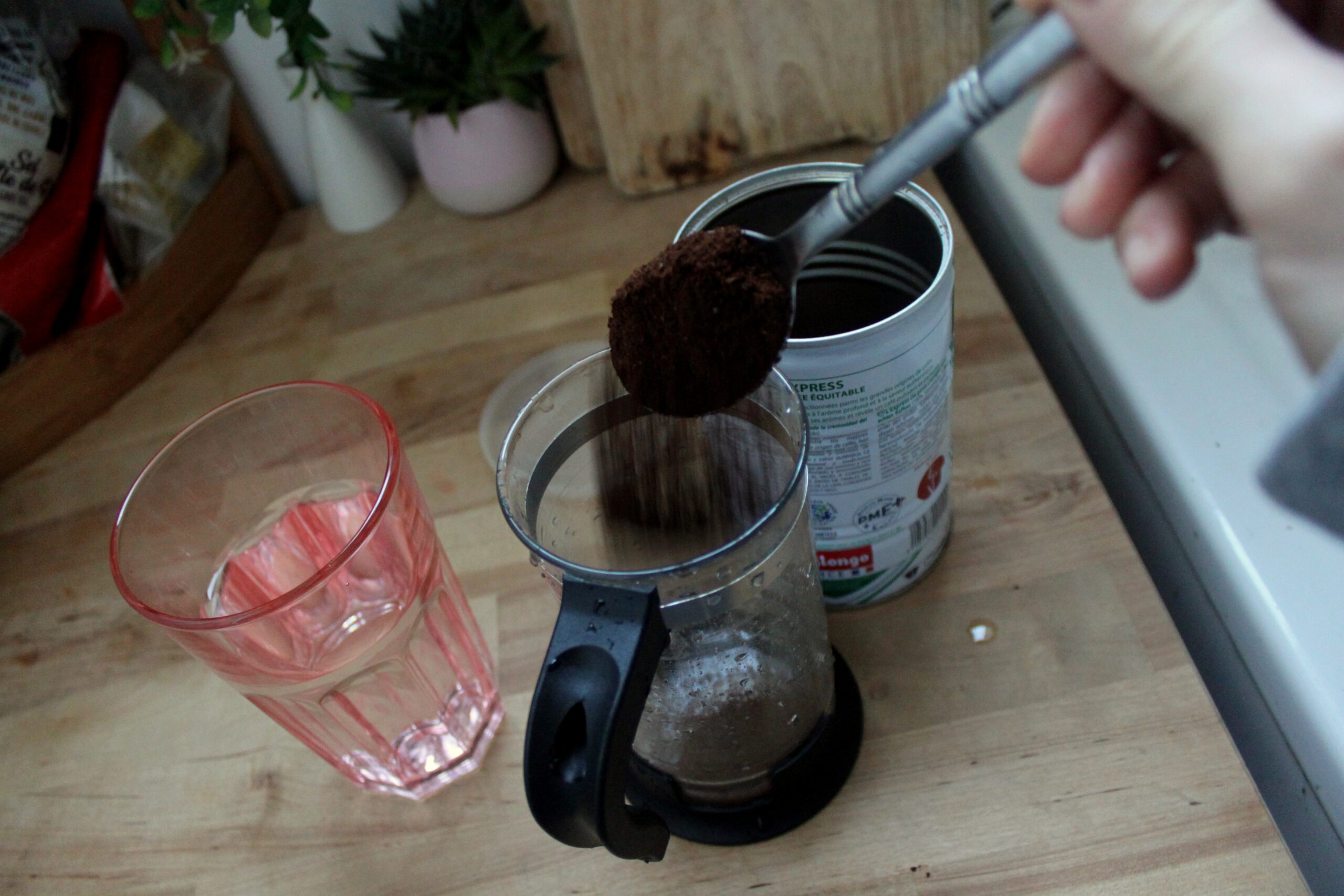 Vu de la cafetière à piston de Nina. Elle verse le café moulu à l'intérieur.