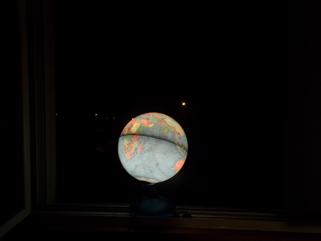 Phographie de la fenêtre de Nathan Florent avec son globe lumineux, de nuit.