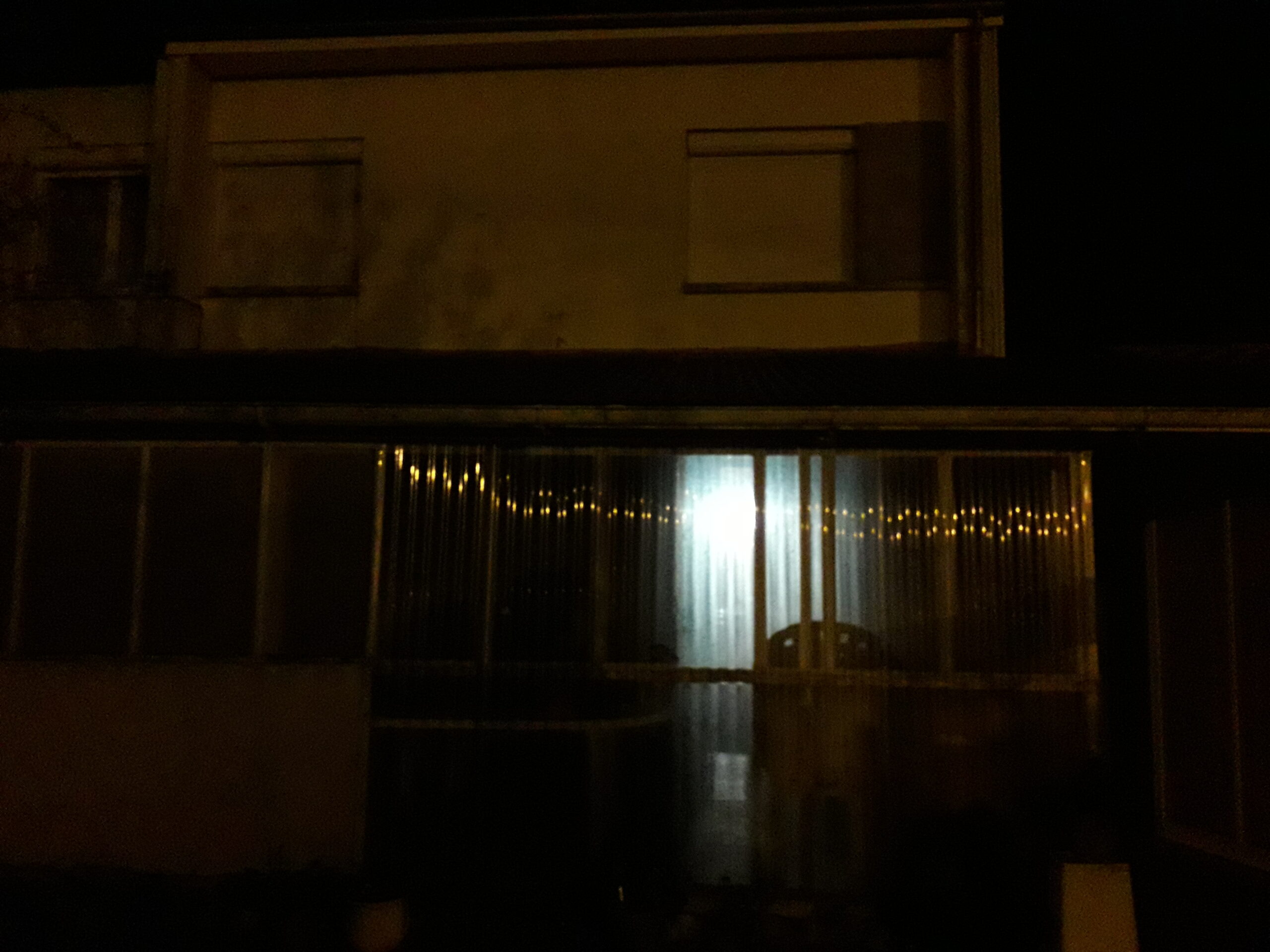 Photographie de la véranda de Nathan Florent de nuit avec les reflets des lampadaires.