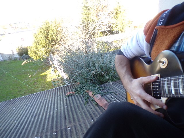 Selfie de Nathan Florent avec sa guitare (Gibson Les Paul) sur le rebord de sa fenêtre, de jour.