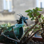 Dragon décoratif sur une jardinière où pousse du lierre.